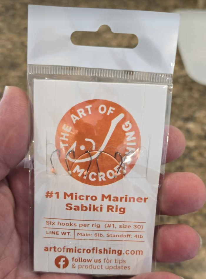 A packet of The Micro Mariner micro fishing sabiki rig, featuring six tiny hooks, alternating colored beads, and durable monofilament lines, neatly packaged on a cardboard line holder with a swivel and snap